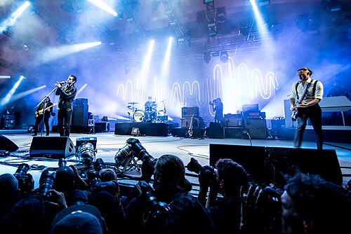 Arctic Monkeys playing on a large festival stage.